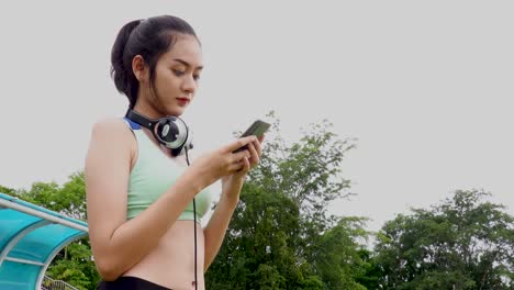 Happy-sporty-woman-with-headphones,-she-is-searching-music-online-using-her-digital-tablet-after-treadmill-exercising-in-stadium,-Sport-and-leisure-activities-concept