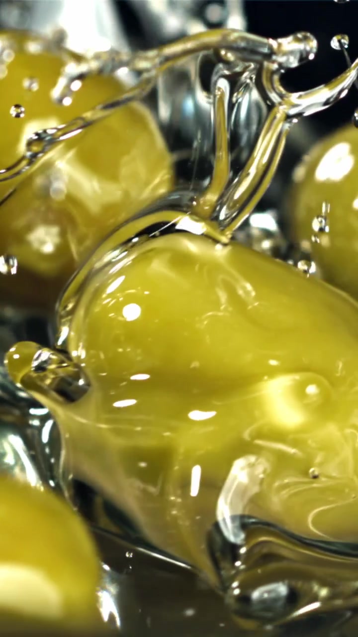 Olive verdi che cadono nell'acqua al rallentatore.