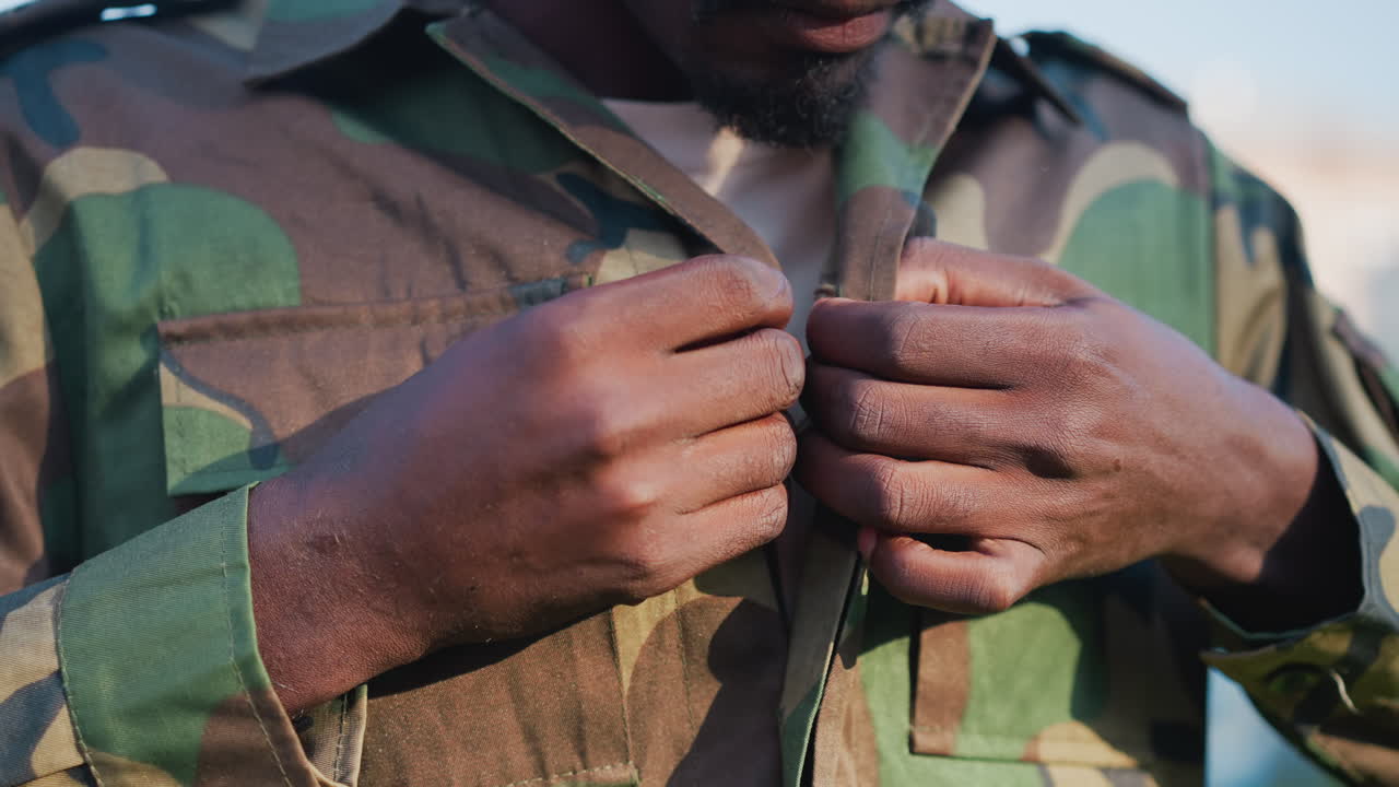 Military Personnel Getting Ready Outdoors, Service Member Meticulously Preparing Camouflage Attire Outside, Military Operative Focusing On Uniform Adjustments During Premission Routine Outdoors