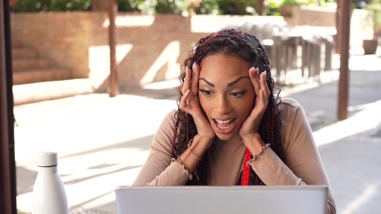 A young woman engaged in productive work on her laptop while relaxing at an outdoor cafe