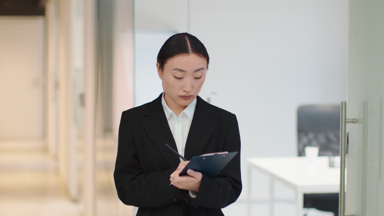 Businesswoman Taking Notes in Office Corridor
