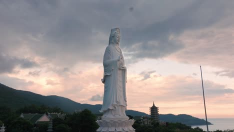 Giant-Statue-of-Buddha-Against-Dramatic,-Moody-Sunset-Sky