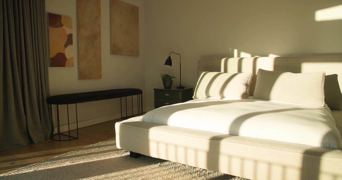 Letto imbottito in camera da letto mentre la telecamera panoramica e la luce del sole si riversano, rivelando una lampada