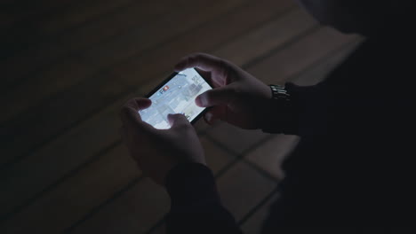 person playing a mobile game in a dark room