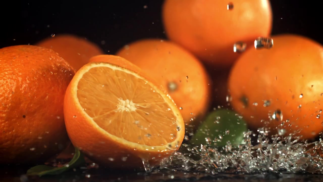Acqua che schizza al rallentatore su arance fresche con foglie verdi