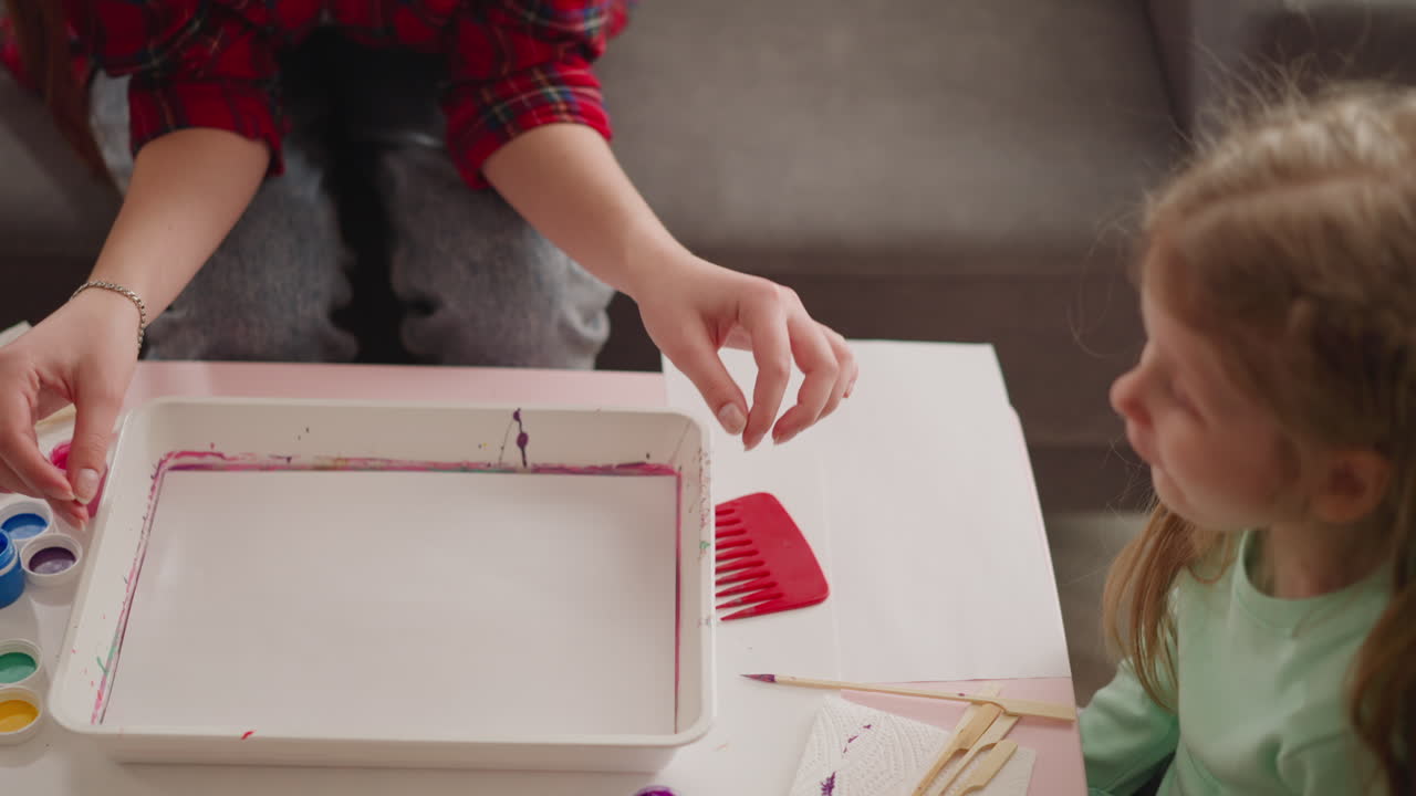 el artista cubre la bandeja con la mezcla de arte ebru en la lección para la niña
