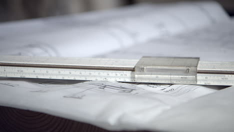 logarithmic ruler on top of technical chart on table, macro pan