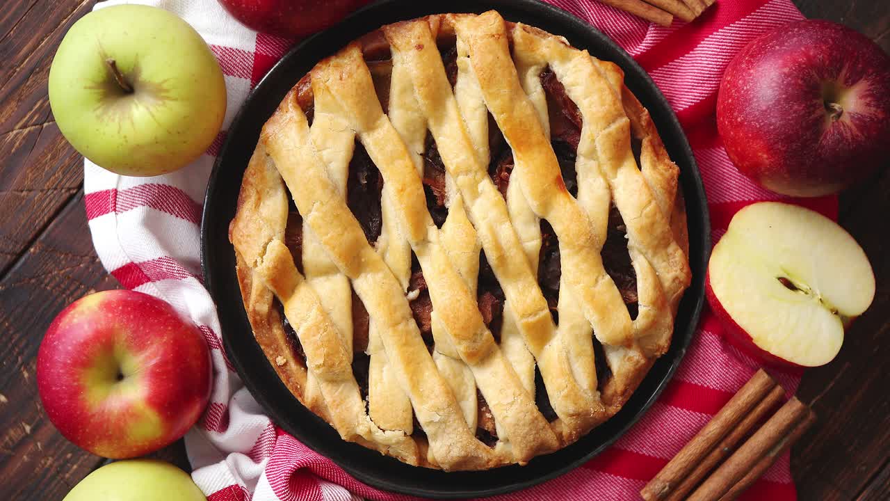 pastel de manzana casero con productos de panadería en la mesa de la cocina de madera oscura