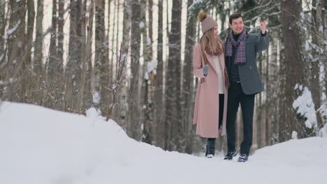 Young-married-couple-in-love-walking-in-the-winter-forest.-A-man-and-a-woman-look-at-each-other-laughing-and-smiling-in-slow-motion.-Valentine's-Day-love-story.