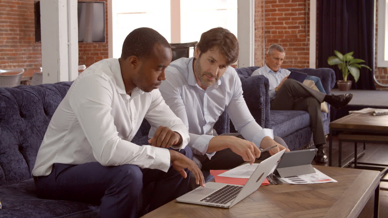 사무실 의 휴식 구역 에서 소파 에서 일 하는 사업가 들