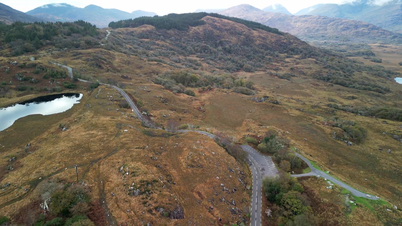 Innsjøer og oransje høstkledde åser med en landevei i Killarney, droneopptak fra luften. Irland