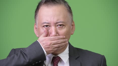 mature japanese businessman covering mouth as three wise monkeys concept