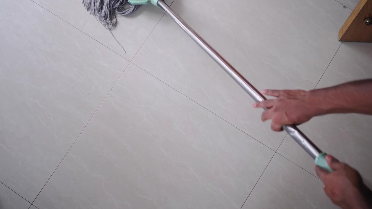 Person som mopper flislagt gulv i et hjemmeinteriør.