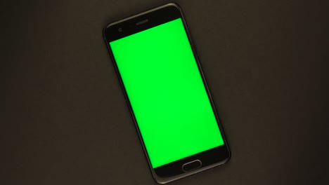 smartphone with green screen rotates on black background