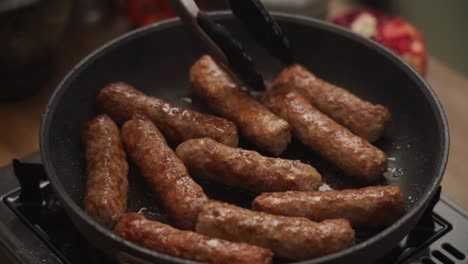 persona de la cosecha girando salchichas caseras fritando en sartén