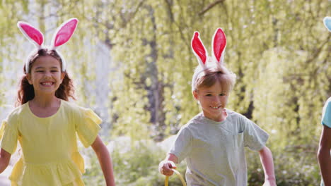 group of children wearing bunny ears running on easter egg hunt in garden