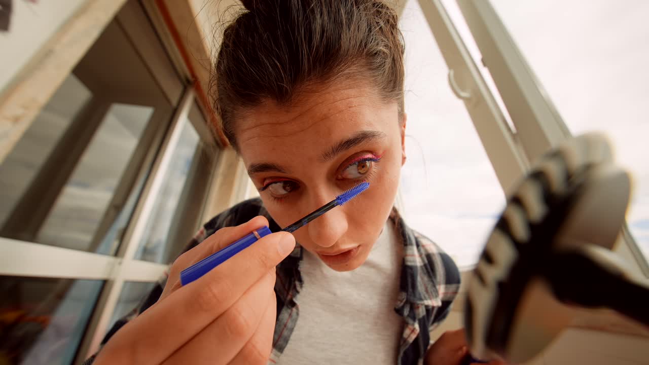 Young Woman Applying Blue Mascara to Her Eyelashes