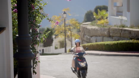 Mujer-Joven-Pasando-En-Su-Scooter-En-Una-Comunidad-Cerrada