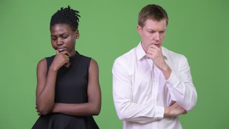 two young serious multi-ethnic business couple thinking together