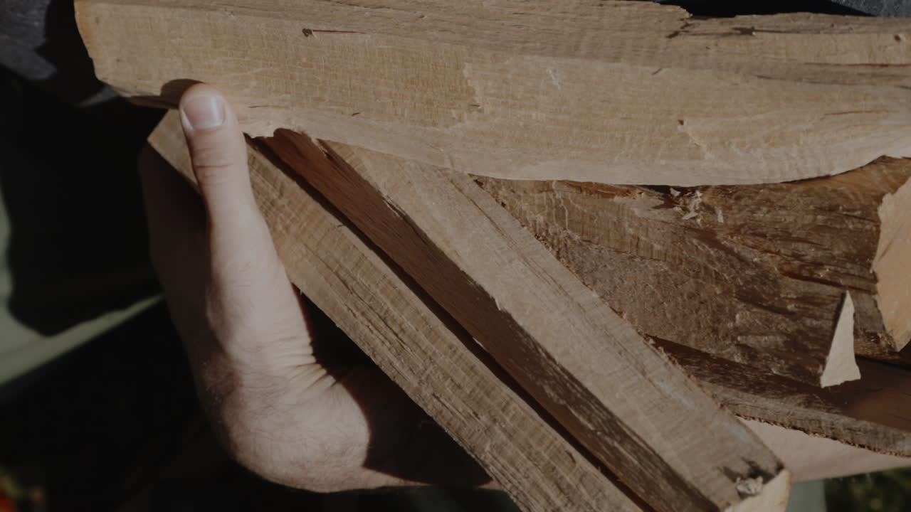 A man picks up wooden logs
