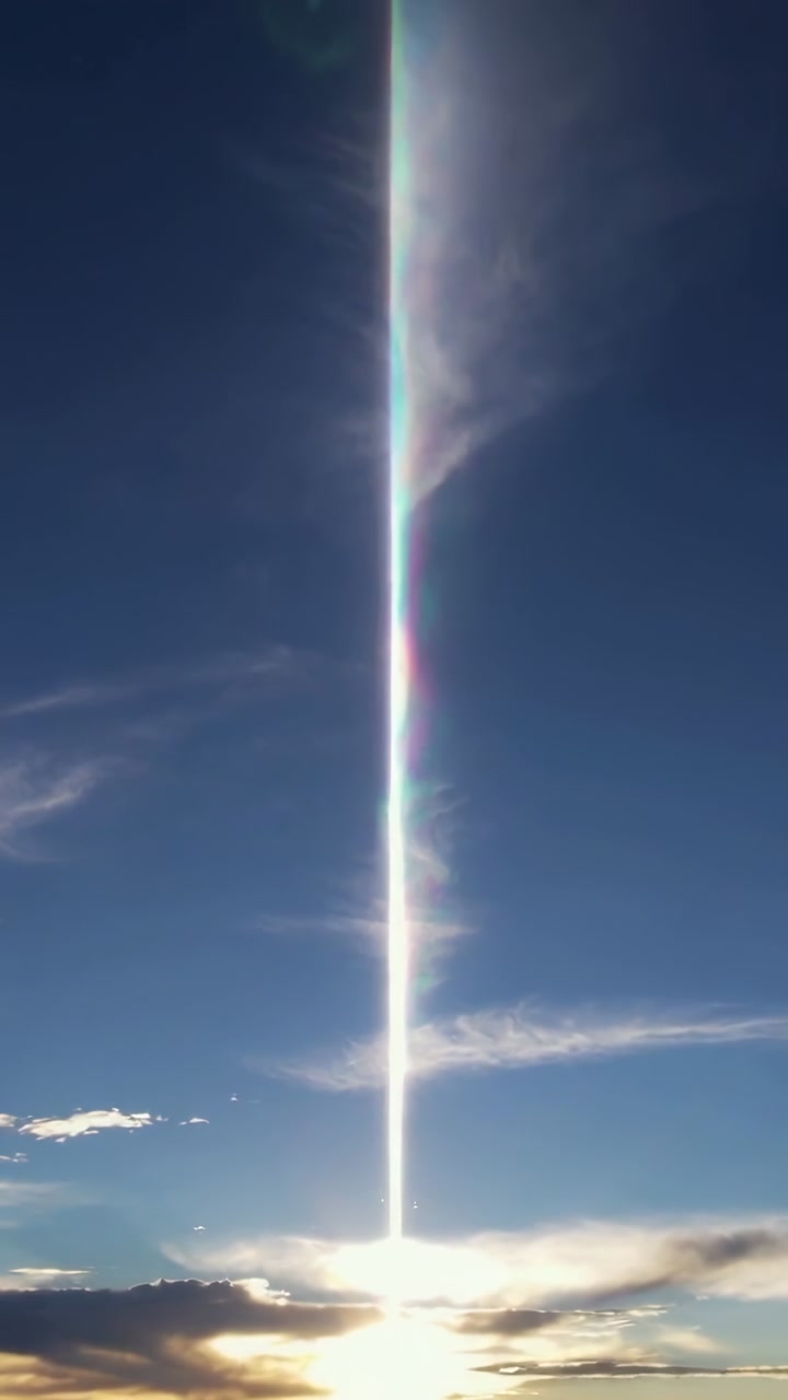 Vertical video: Nearing horizon sun and narrow beam casting upward over clouds with rainbow edges