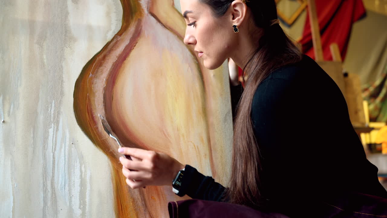 Close up of a woman painting on a canvas at an art gallery workshop