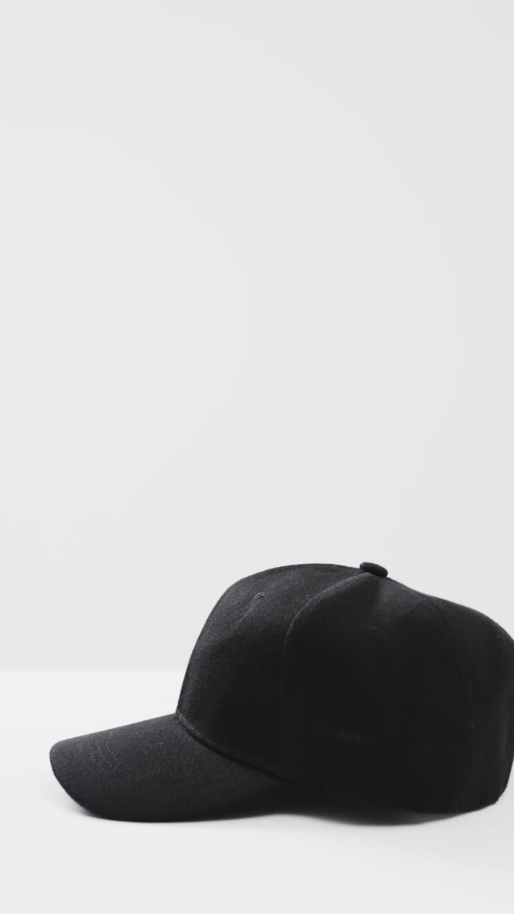 Vertical video of black baseball cap and copy space on white background