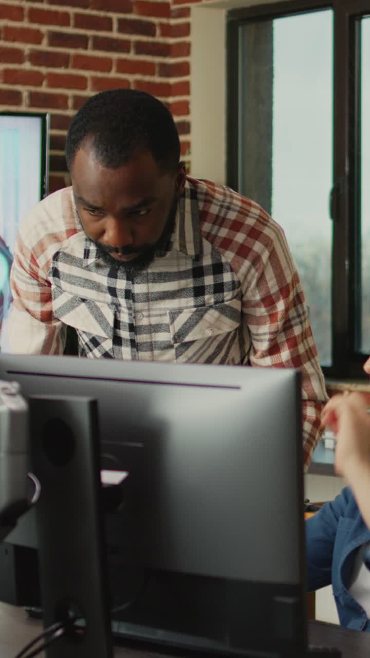 Vertical video: Smiling coworker talking to 3D developer about digital art production