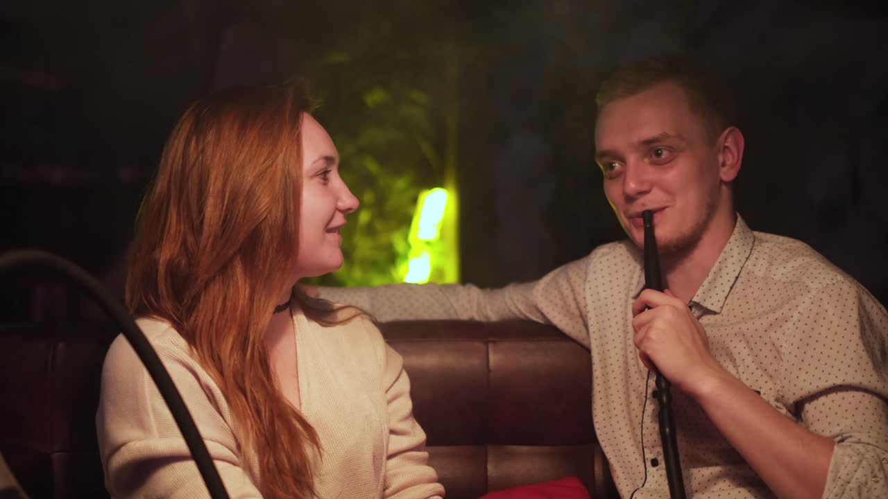 una pareja disfrutando de un narguile en un salón.