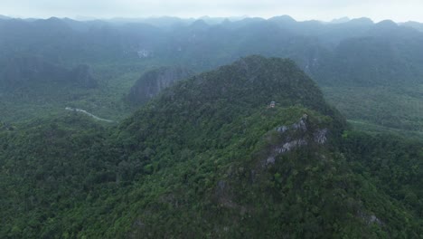 cinematic drone zoom in over steep green mountain surrounded by dense jungle in cat ba