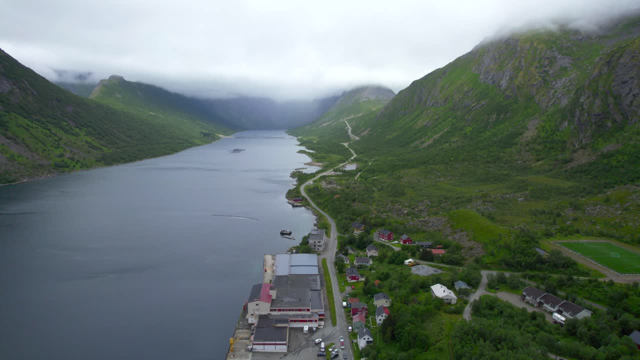 dolly retrocedió revelando el pequeño pueblo de gryllefjord con una increíble vista de las empinadas montañas cubiertas de nubes que rodean el fiordo.