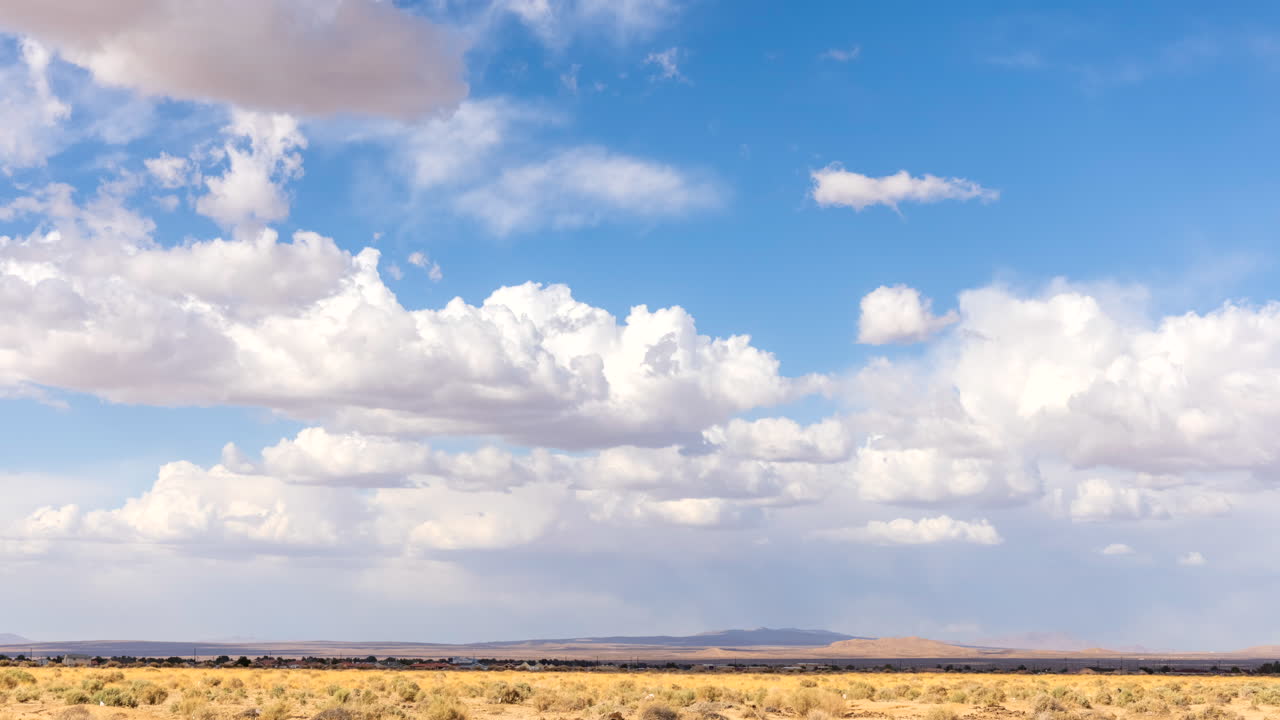 grandes nubes de cúmulo esponjosas son empujadas por el viento caliente sobre el paisaje del desierto de mojave - lapso de tiempo estático