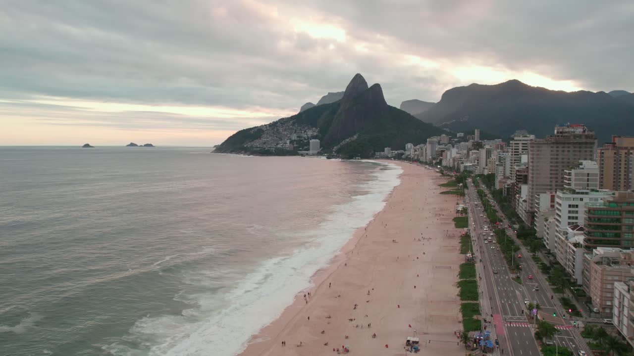 flyover estableciendo sobre la playa de ipanema en brasil con la colina dos irmaos en el fondo en el atardecer nublado