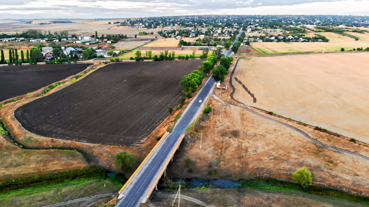 Aerial drone view of a road with moving car in highland. Green fields and hills from north part of Moldova
