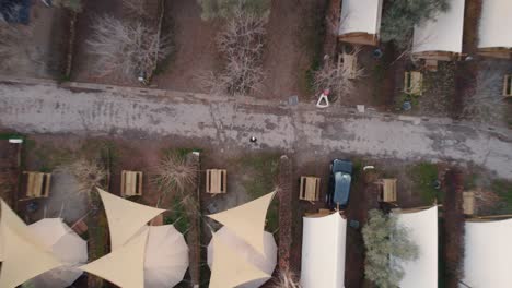 top down descending aerial view camping canvas tent plot rows in autumn woodland