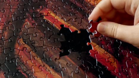 a hand works on a colorful puzzle