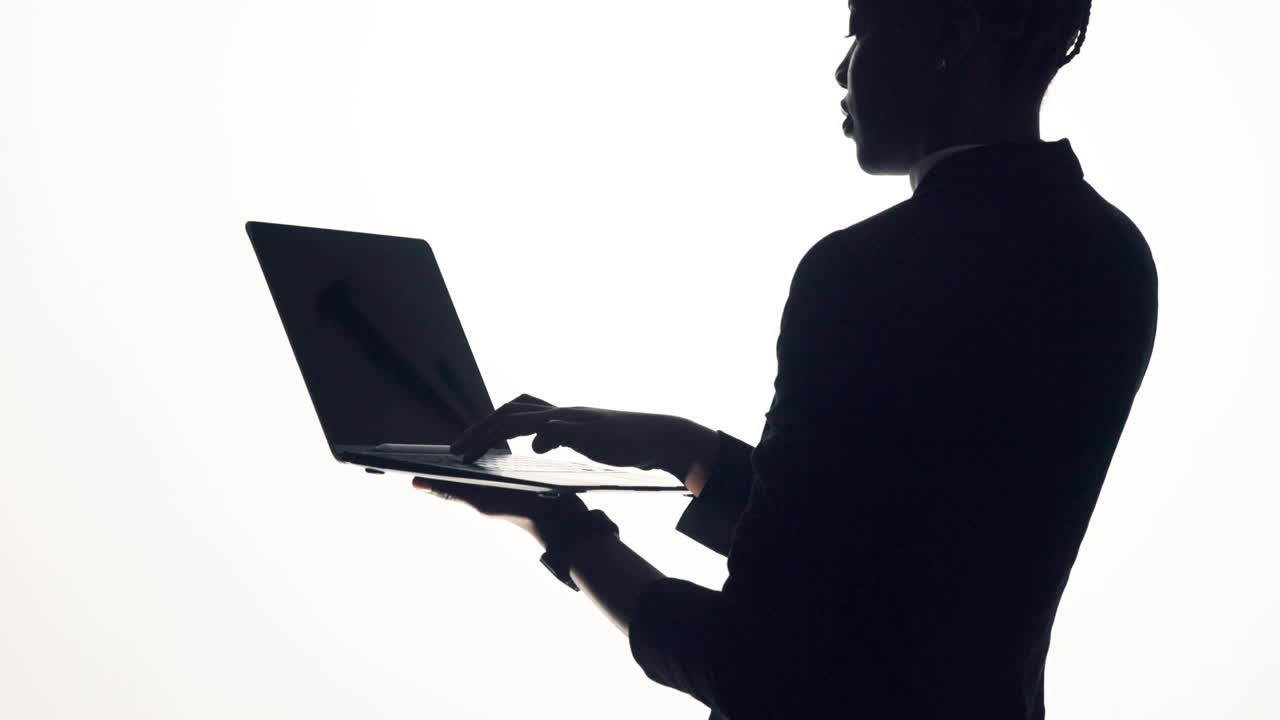 Silhouette of a person thinking while holding a laptop