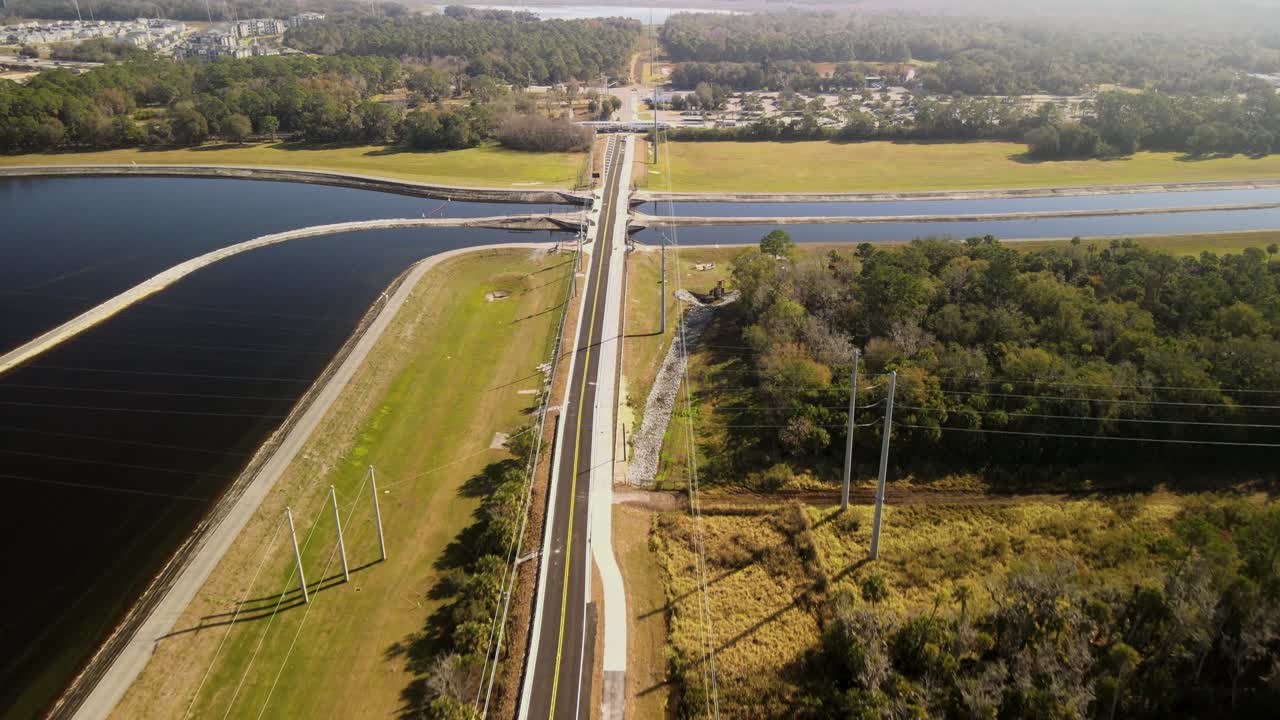 Drone flyr over vei ved siden av innsjø og trær i Florida