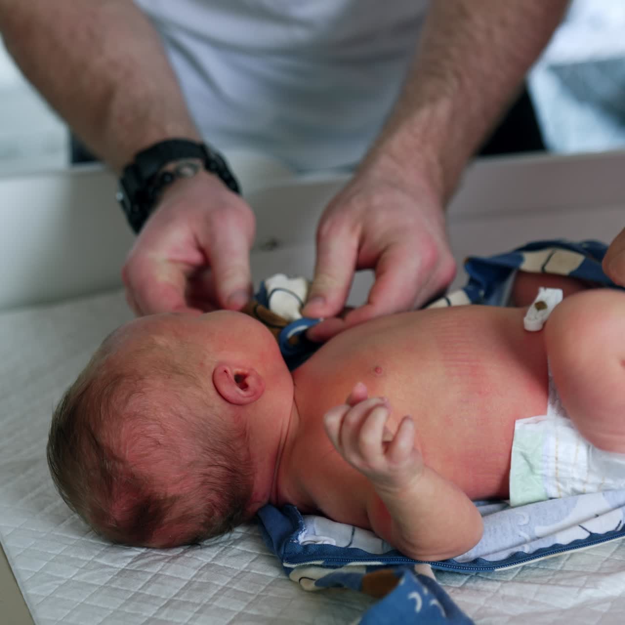Healthy Caucasian newborn lies on the table. Child is dressed by his parents. Top view