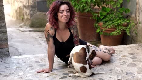 relaxed woman sitting in the ground plays with her dog- outdoor