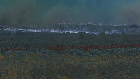 aerial view of waves softly crashing to the shore in iceland