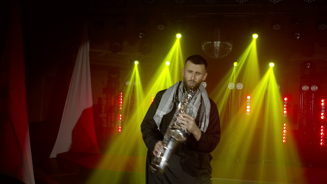actuación en vivo del saxofonista hombre con saxofón, bailando en el escenario del músico de concierto con luces
