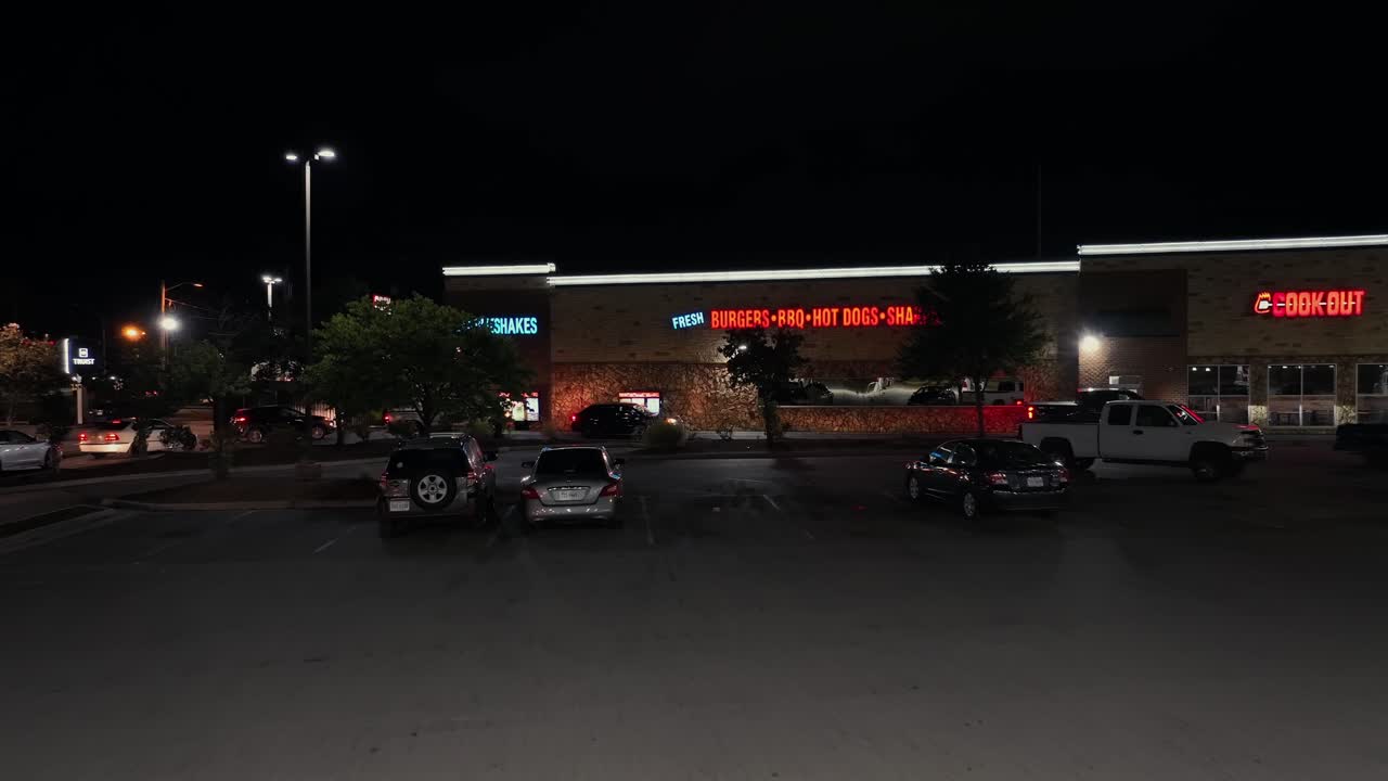 Aerial flight through empty lighting gas station in USA. Approaching Cook Out Restaurant in suburb of american town.