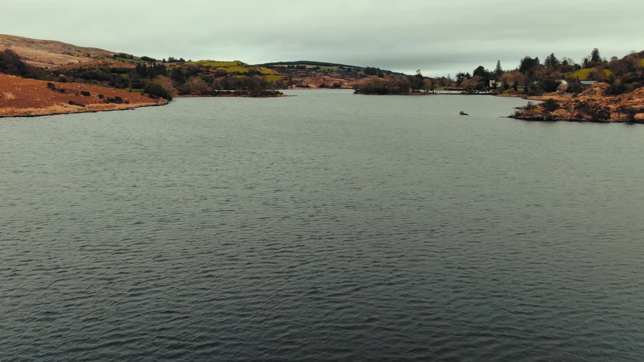 Drone flying low over a lake approaching and passing small island