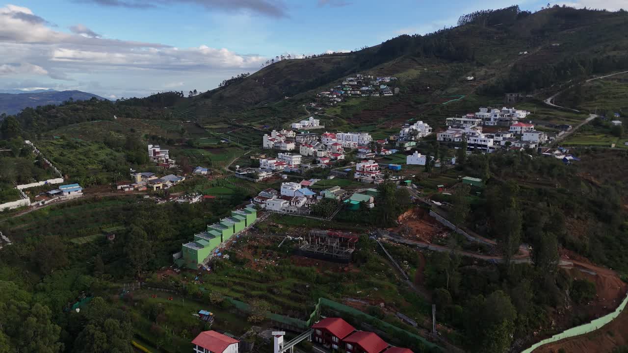 Drone footage flying past pine-covered slopes and valley cottages