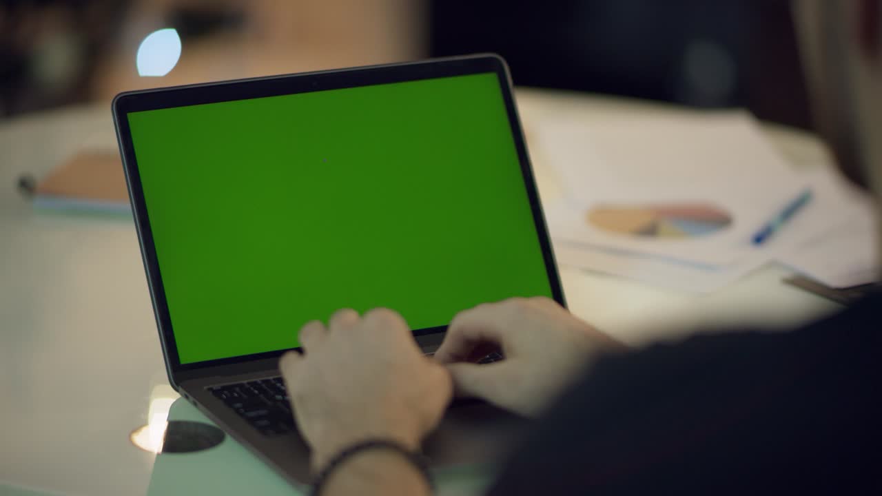 manos del hombre trabajando en una computadora portátil con pantalla verde