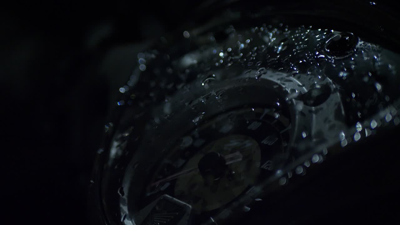 어두운 밤에 오토바이의 스피도미터 위에 비방울이 떨어집니다.