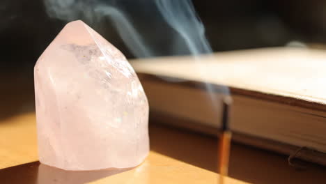 rose quartz crystal with incense and book