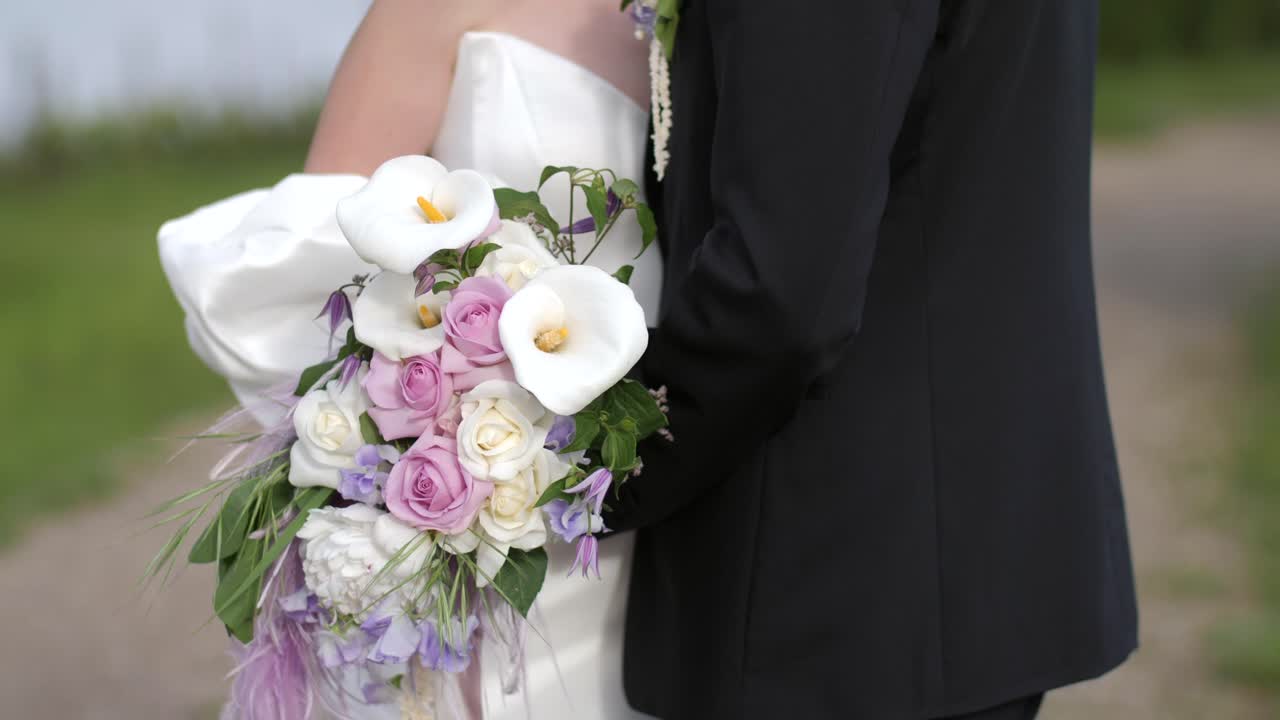 novios abrazándose en una carretera de grava, flores enfocadas, primer plano a cámara lenta