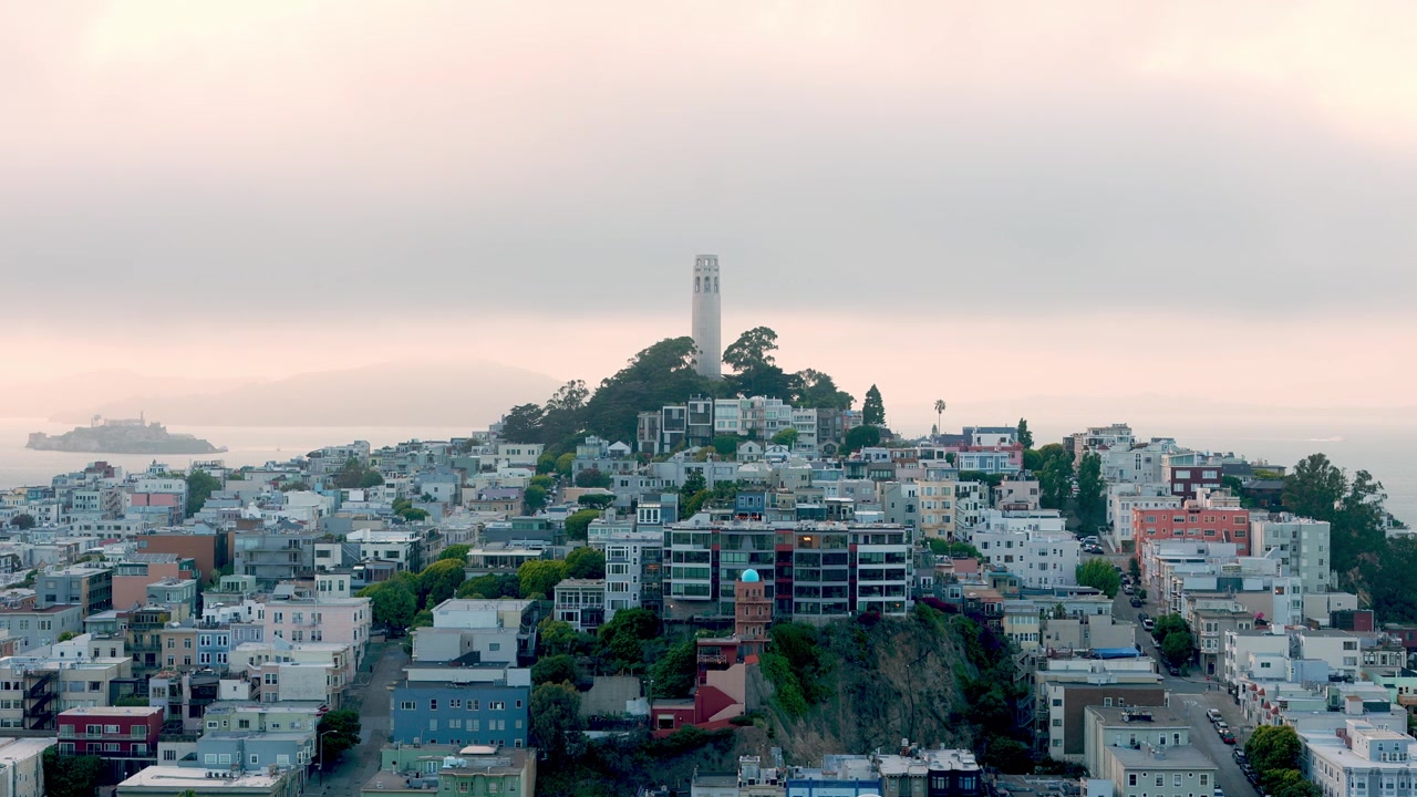 Vista elevada del barrio de North Beach de San Francisco con la icónica Torre Coit en Telegraph Hill y la Isla de Alcatraz en la bahía durante un atardecer nublado y con niebla